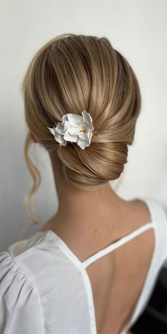 53 Best Wedding Hairstyles For 2023 Brides : Simple Low Bun With White Flower  Hair Pin Throughout Low Flower Bun For Long Hair (View 4 of 25)