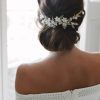 Wavy Low Bun Bridal Hairstyles With Hair Accessory (Photo 15 of 25)